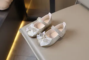 Detalle de zapatos de princesa dorados para niñas con lazo brillante y pedrería