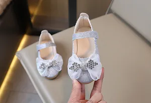 Detalle de zapatos plateados para niña con lazo de encaje y brillantes de diamantes