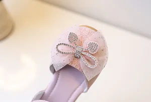 Detail von rosa glitzernden Mädchenschuhen mit Strass-Schleife und Herzverzierung
