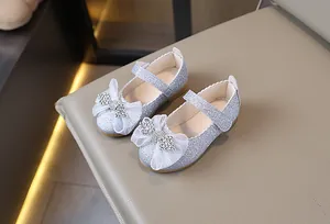 Detalle de zapatos de princesa plateados con lentejuelas y lazo de tul con diamantes