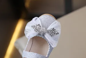 Primer plano de zapatos de princesa plateados con lazo de cristal y detalles de encaje