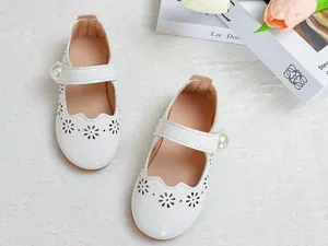 Détail de babies en cuir verni blanc avec découpes florales au laser et boucle en perle