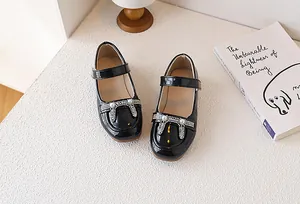 Dettaglio di ballerine Mary Jane nere in vernice con fiocco di strass e perline