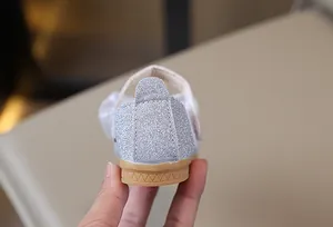 Detalle de tela plateada brillante y suela de goma antideslizante en zapato de niña princesa