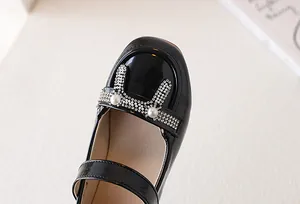 Dettaglio scarpe Mary Jane in vernice nera lucida con decorazione a orecchie di coniglio