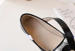 Dettaglio macro di scarpe Mary Jane in vernice nera con accenti di perle e strass