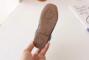 Dettaglio suola antiscivolo in gomma di scarpa in pelle nera da bambina con fiori