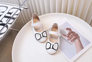 Dettaglio di scarpe Mary Jane bianche da bambina con fiocco e chiusura a strappo