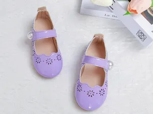 Détail de chaussures Mary Jane en cuir verni violet avec fleurs ajourées et bride à perle
