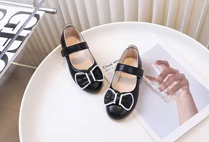 Dettaglio di scarpe Mary Jane nere da bambina con fiocco e cinturino in velcro
