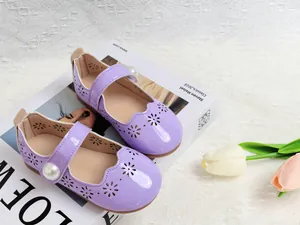 Détail de babies en cuir verni violet avec fleurs découpées au laser et boucle perle