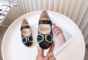 Dettaglio scarpe Mary Jane nere da bambina in pelle martellata con fiocco grande