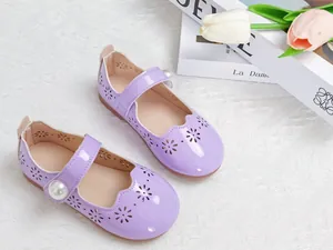 Gros plan de chaussures Mary Jane mauves avec motifs floraux perforés et détail perle