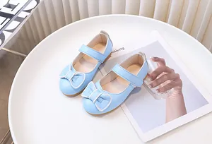 Dettaglio di ballerine Mary Jane blu da bambina con fiocco e cinturino a strappo su piatto