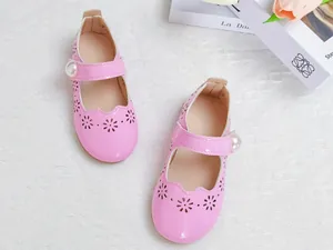 Détail de chaussures Mary Jane roses en cuir verni avec fleurs ajourées et bride à perle