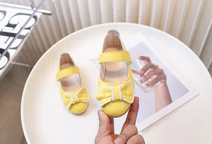 Dettaglio di scarpe Mary Jane gialle per bambina con fiocco e chiusura a strappo