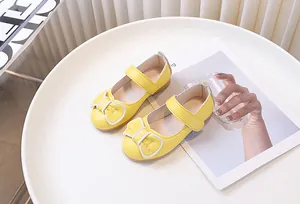 Dettaglio delle scarpe basse Mary Jane gialle con fiocco e trama in pelle martellata