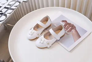 Detalle de zapatos Mary Jane blancos para niña con hebilla de flor y perla elegante
