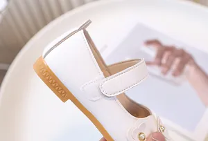 Detalle de zapatos Mary Jane blancos para niña con flores 3D y centro de perlas