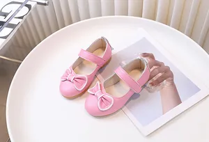 Dettaglio di scarpe Mary Jane rosa da bambina con fiocco e cinturino a strappo
