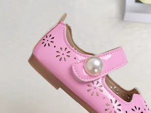 Détail de chaussures Mary Jane en cuir verni rose avec motifs floraux ajourés et perle