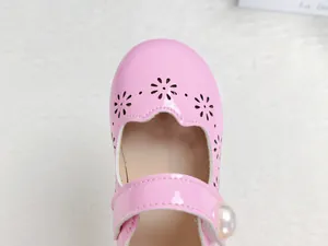 Gros plan de chaussures roses vernies pour filles avec découpes de fleurs et perle décor