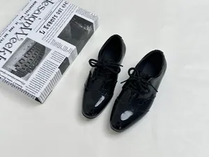 Detail view of black croc-embossed patent leather boy's oxford shoes with lace-up design