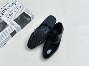 Top view of boys black patent leather dress shoes with crocodile texture on a white background