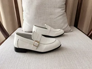 Detail of white crocodile pattern loafers for boys with gold metal buckle on top