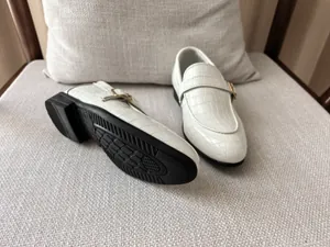 Detail of white crocodile pattern loafer for boys featuring an elegant gold buckle