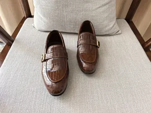 Close-up of brown crocodile embossed leather loafers with gold metal buckle detail