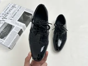 Detail of boys' black patent leather oxford shoes with stylish crocodile pattern texture