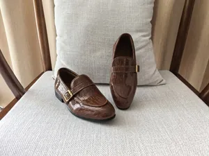Close-up of boys dark brown loafers featuring embossed crocodile leather and buckle
