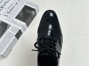 Detail of boys' black leather oxford shoes with patent toe and crocodile texture finish