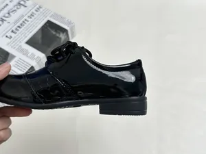 Detail view of boys black patent leather oxford shoes with stylish crocodile embossed pattern