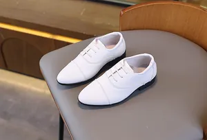 Détail de chaussures Oxford blanches pour garçons avec semelles noires sur siège cuir