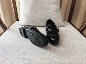Close-up of black crocodile pattern leather boy loafers with gold buckle detail