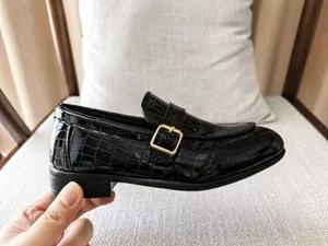 Detail of boys black crocodile embossed loafers with golden square metal buckle