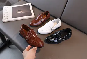 Dettaglio di scarpe monk per bambini in marrone, bianco e nero con pelle motivo coccodrillo