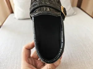 Macro shot of black crocodile texture loafers for boys with shiny gold metal buckle