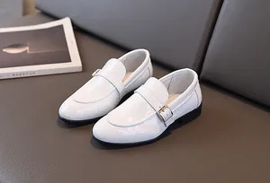 Dettaglio scarpe bianche da bambino con motivo a coccodrillo e fibbia dorata