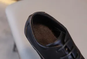 Détail de la doublure en maille respirante noire et texture du cuir sur chaussures de garçon