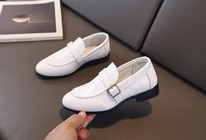 Dettaglio scarpe eleganti bianche da bambino con trama a coccodrillo e fibbia in metallo