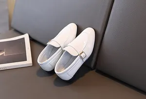 Dettaglio scarpe eleganti bianche da bambino in vernice coccodrillo con fibbia d'oro