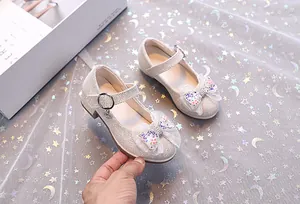 Détail des chaussures Mary Jane pailletées avec nœud en dentelle et breloques strass