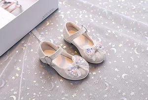 Gros plan de chaussures Mary Jane argentées à paillettes pour filles avec nœud en dentelle
