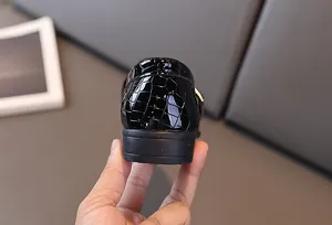 Dettaglio macro del tallone in pelle verniciata goffrata coccodrillo nero per scarpe ragazzo
