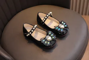 Dettaglio di scarpe da principessa nere glitterate con cinturino di perle da bimba