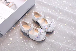 Détail de chaussures Mary Jane à paillettes argentées avec nœud en tulle et fleurs perlées