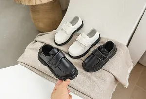 Detail of kids leather dress shoes with velcro straps in black and white colors
